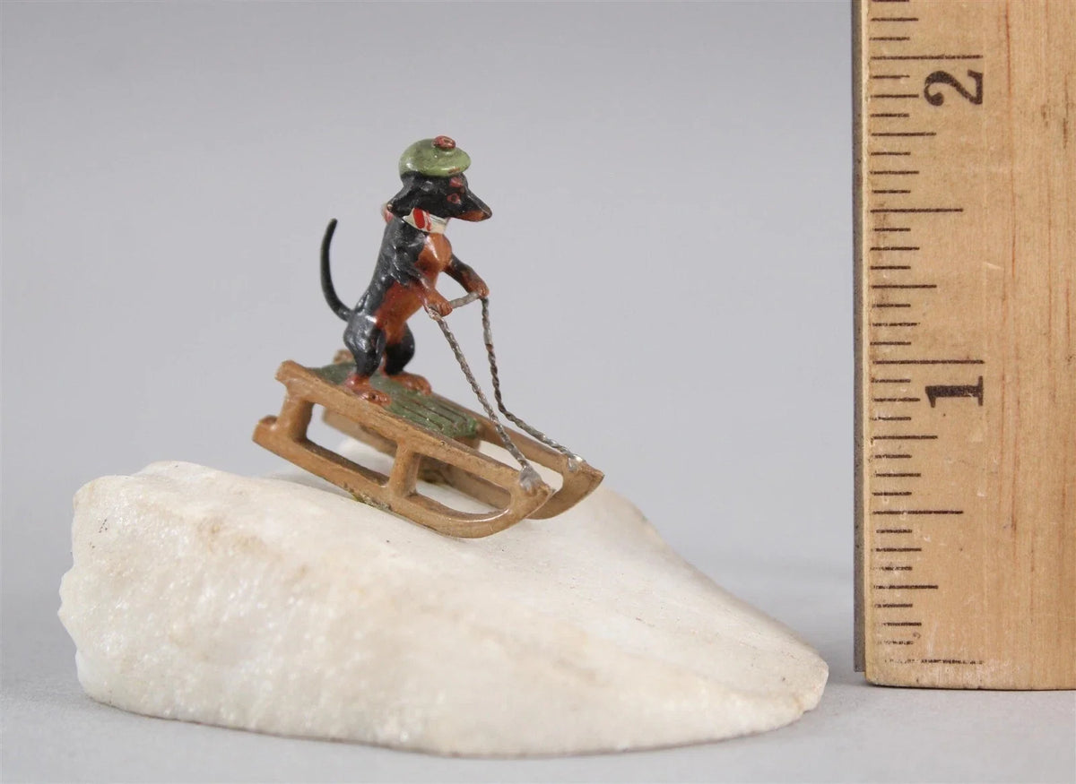 Sculpture miniature antique autrichienne en bronze représentant un teckel faisant du traîneau dans la neige.