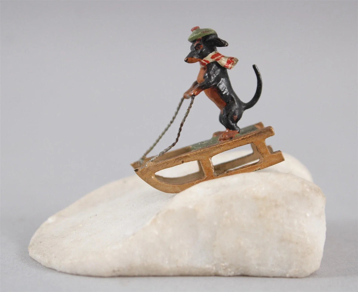 Sculpture miniature antique autrichienne en bronze représentant un teckel faisant du traîneau dans la neige.
