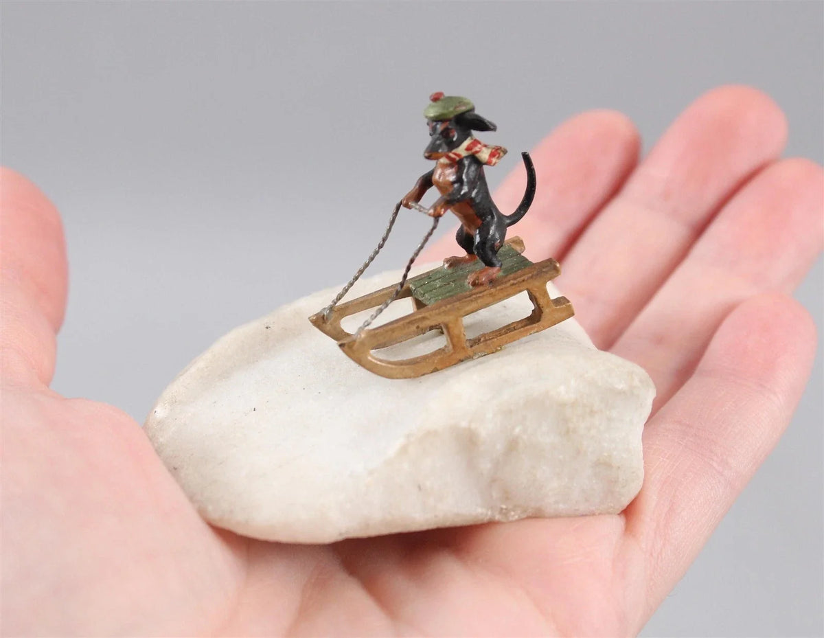 Sculpture miniature antique autrichienne en bronze représentant un teckel faisant du traîneau dans la neige.
